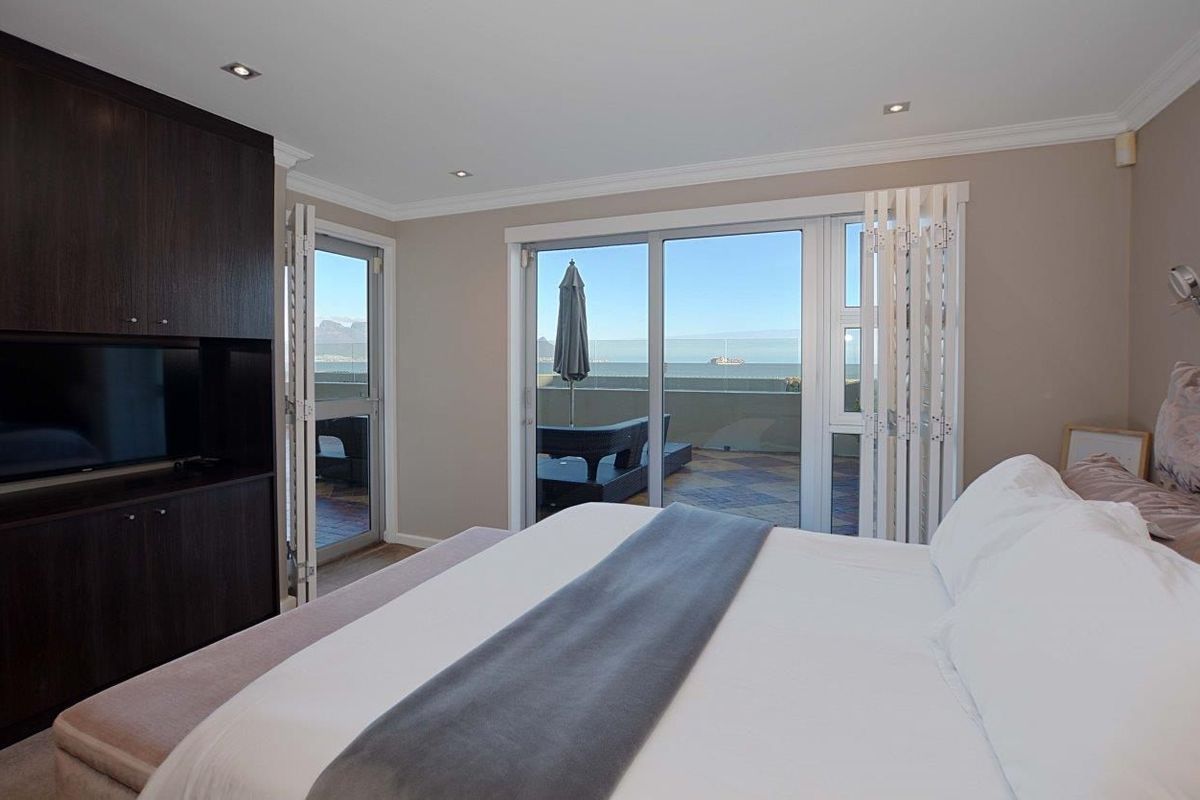 Spacious bedroom featuring built-in cabinetry, recessed lighting, and large sliding glass doors that open onto a private balcony with ocean views.