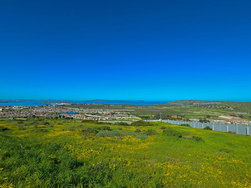 Expansive elevated view overlooking the surrounding landscape, coastal town, and ocean horizon from the vacant residential land.