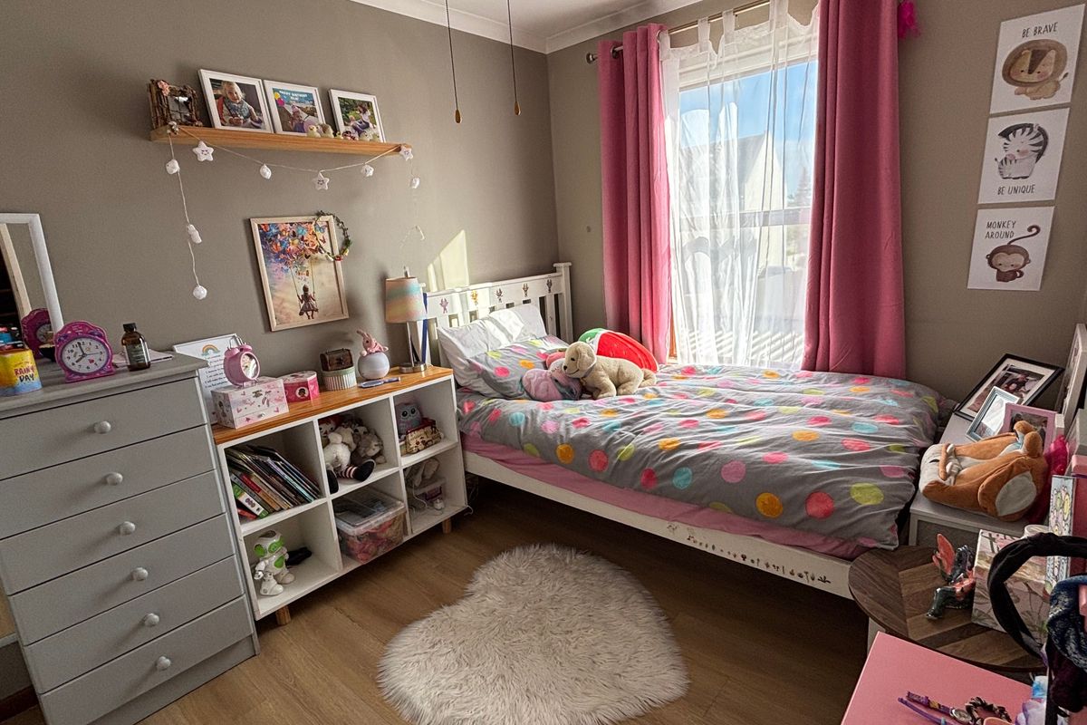 A well-maintained bedroom featuring laminate flooring, a ceiling fan, and neutral wall finishes, providing a comfortable and functional living space.