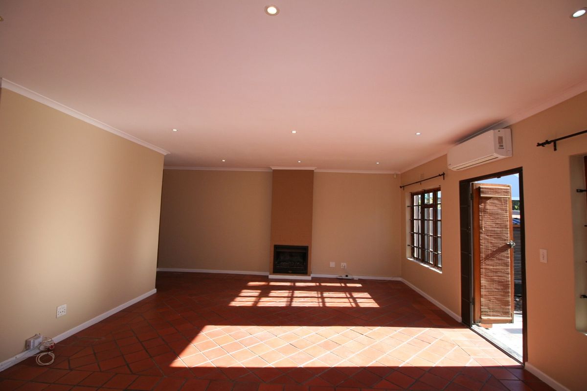 Spacious living room featuring terracotta tile flooring, a built-in fireplace, recessed lighting, and direct access to the outdoors via a glass-panelled door.