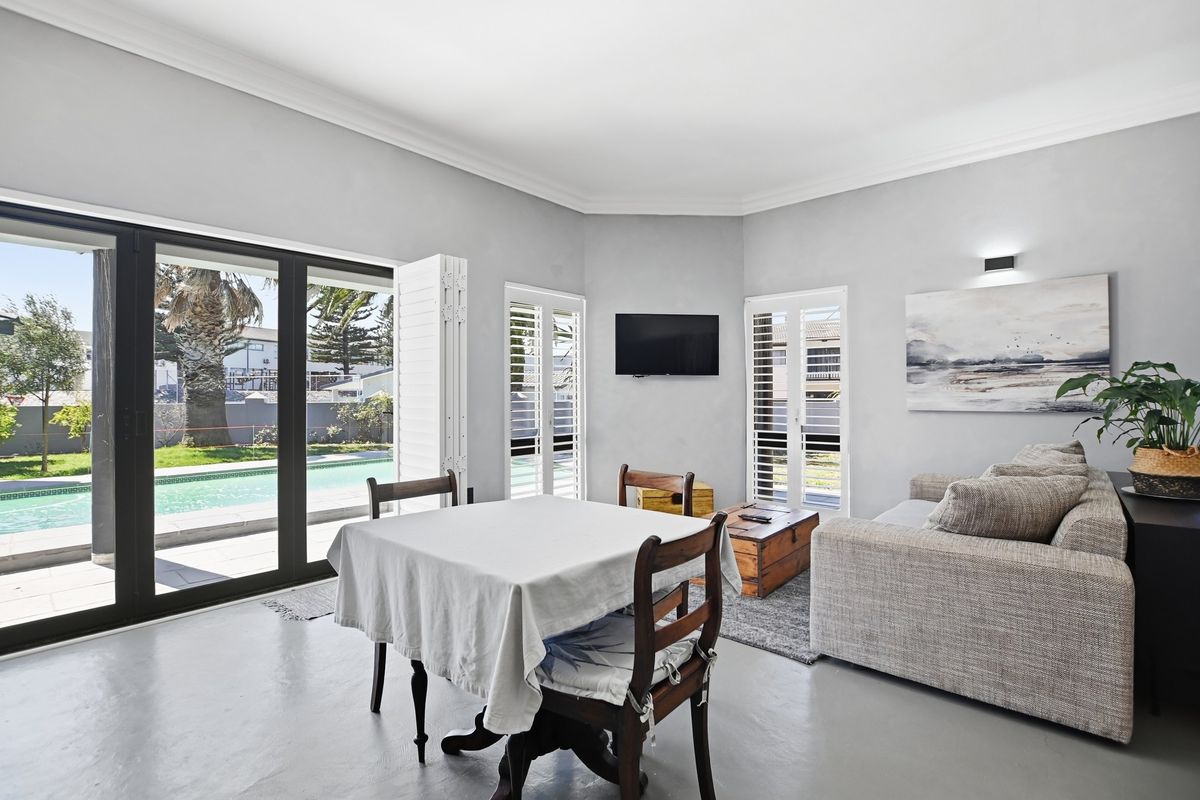 Bright living area featuring polished concrete floors, cove ceilings, and large sliding glass doors providing direct access to the pool area.