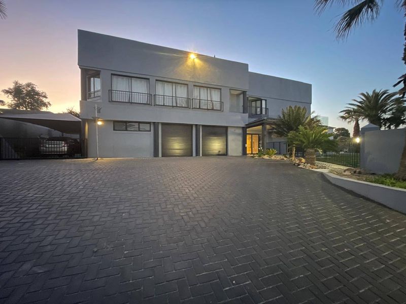 Modern double-story residence featuring a paved driveway, double garage, and upper-level balcony, presented in a well-maintained contemporary architectural style.
