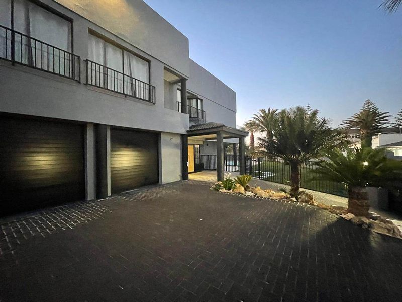 Modern double-story residence featuring a paved driveway, double garage, and covered entrance with balcony access.