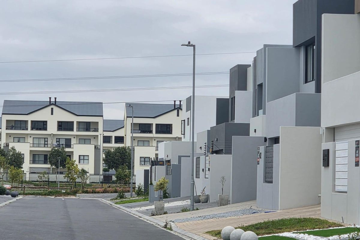 A street-level view of a modern residential estate featuring contemporary townhouses with clean architectural lines and paved driveways.