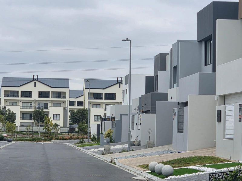 A street-level view of a modern residential estate featuring contemporary townhouses with clean architectural lines and paved driveways.