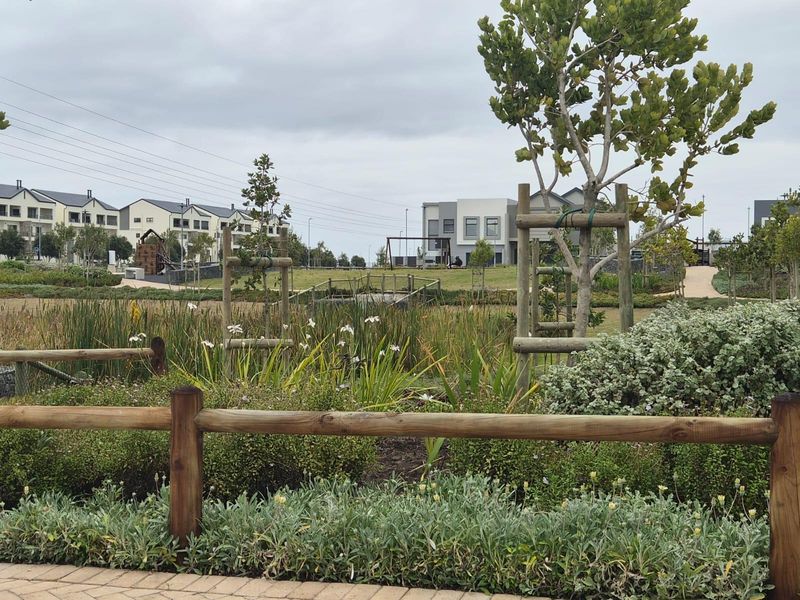A well-maintained communal garden area featuring a wetland, timber fencing, and landscaped greenery within a residential estate setting.