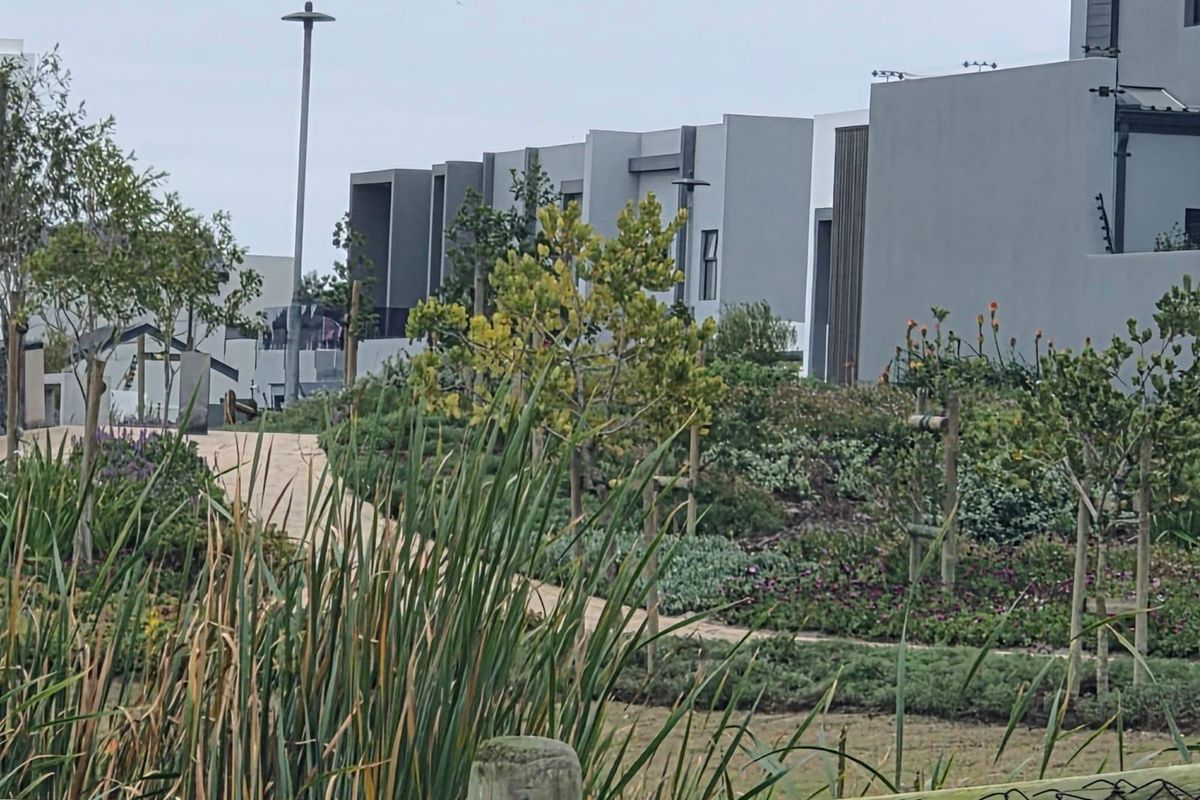 A view of a modern residential complex featuring landscaped gardens, paved pathways, and contemporary architectural facades.