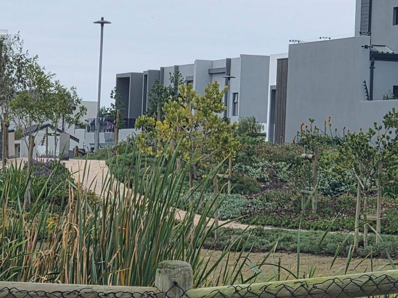 A view of a modern residential complex featuring landscaped gardens, paved pathways, and contemporary architectural facades.