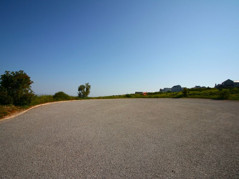 A view of a gravel road surface and surrounding landscape in a residential area.
