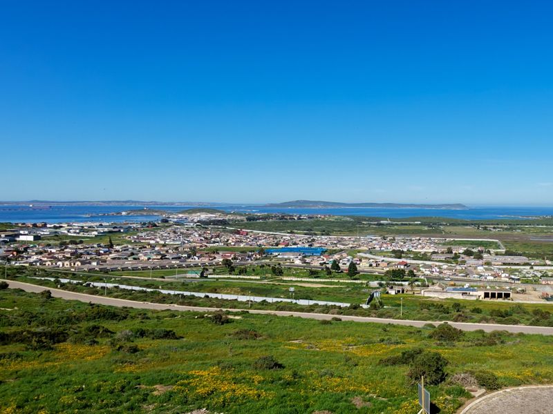 An elevated aerial view overlooking the surrounding residential landscape, coastal area, and distant horizon under a clear blue sky.