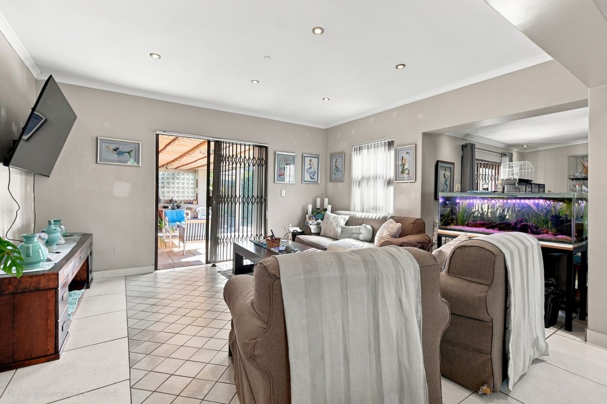 A spacious living room featuring tiled flooring, recessed downlights, and a sliding glass door providing direct access to the outdoor patio area.