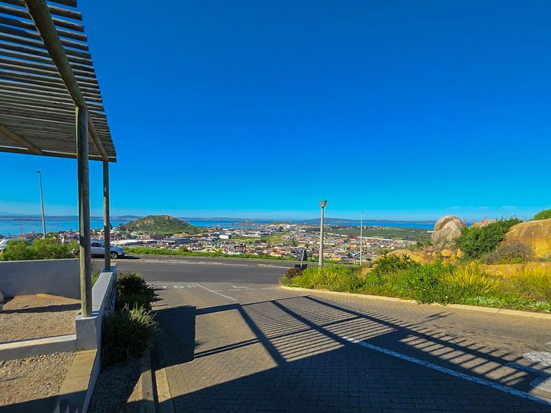 Elevated view overlooking the surrounding town and coastal landscape, featuring a paved driveway and a timber pergola structure in the foreground.