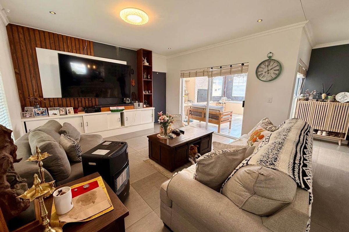 Spacious living room featuring tiled floors, built-in cabinetry with a wood panel feature wall, and sliding glass doors leading to an outdoor patio area.