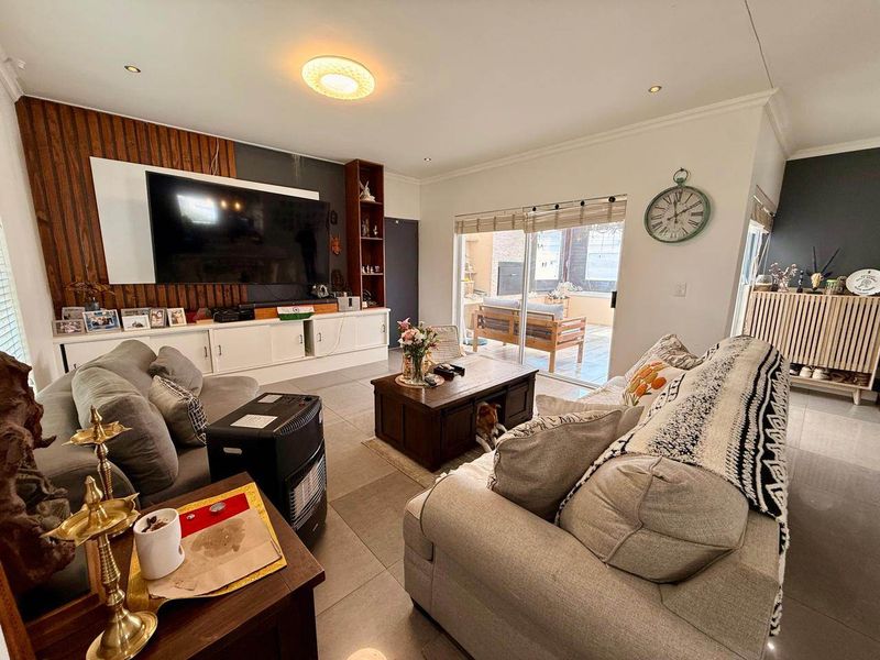Spacious living room featuring tiled floors, built-in cabinetry with a wood panel feature wall, and sliding glass doors leading to an outdoor patio area.