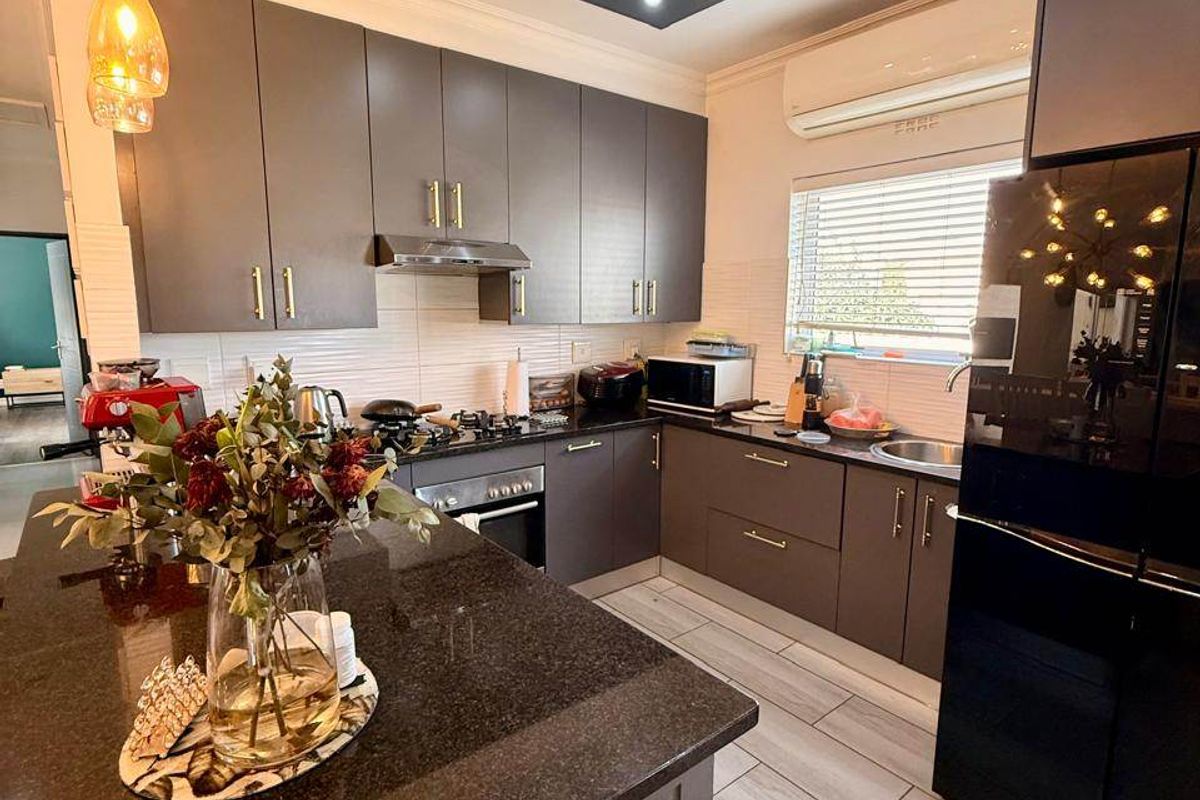Modern kitchen featuring dark cabinetry, granite countertops, a central island, built-in appliances, and recessed ceiling lighting.