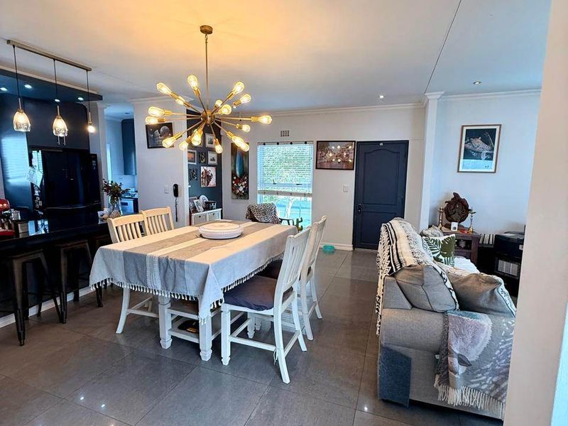 Spacious open-plan living and dining area featuring large format porcelain floor tiles, modern lighting, and a sleek kitchen island with integrated cabinetry.