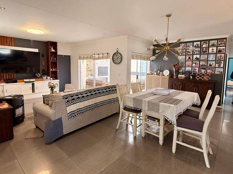 Spacious open-plan living and dining area featuring tiled flooring, modern lighting, and direct access to the outdoor patio through sliding glass doors.
