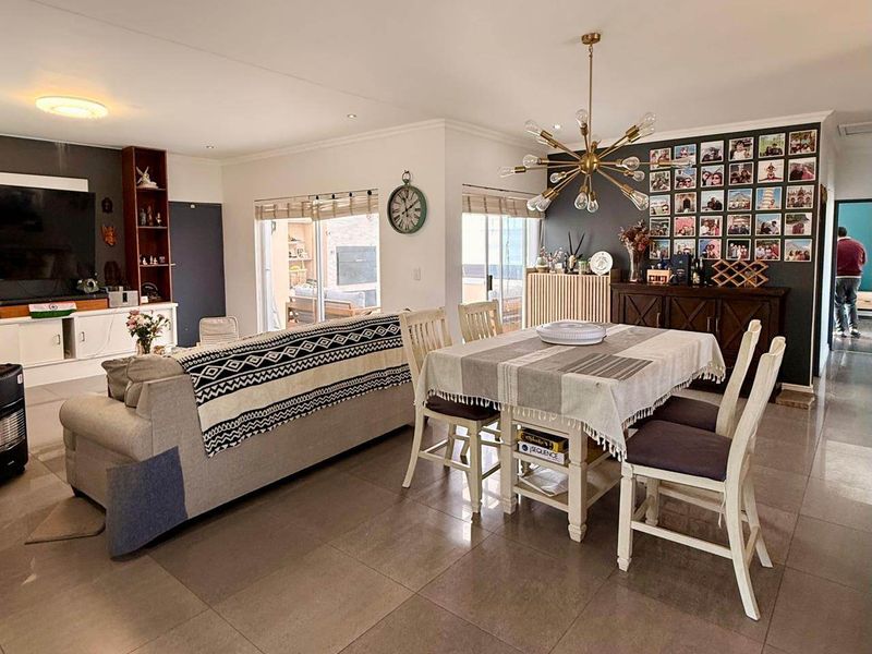 Spacious open-plan living and dining area featuring large format floor tiles, recessed lighting, and sliding doors providing access to the outdoor patio.