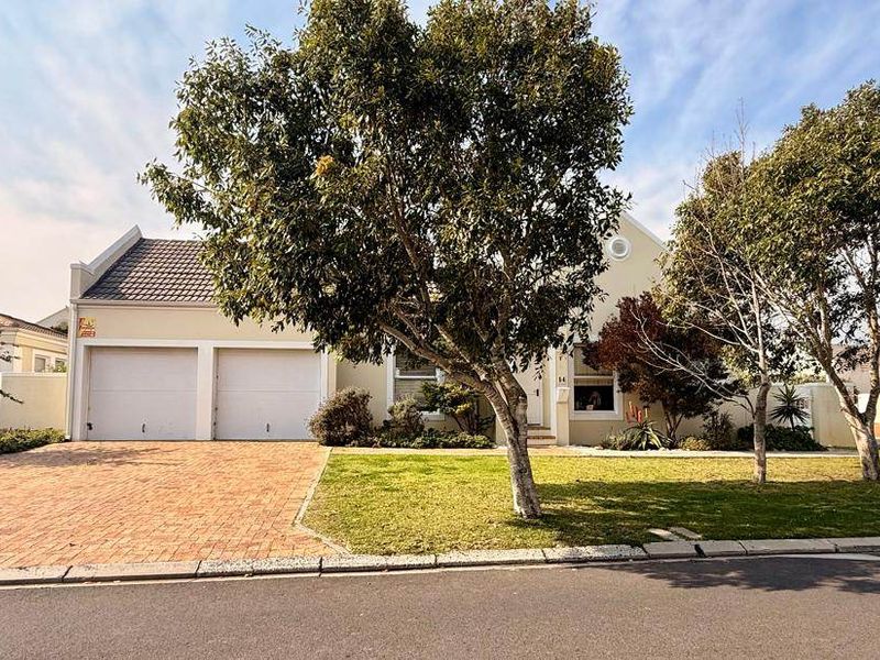 Front elevation of a residential property featuring a double garage, brick paved driveway, and a well-maintained front garden.