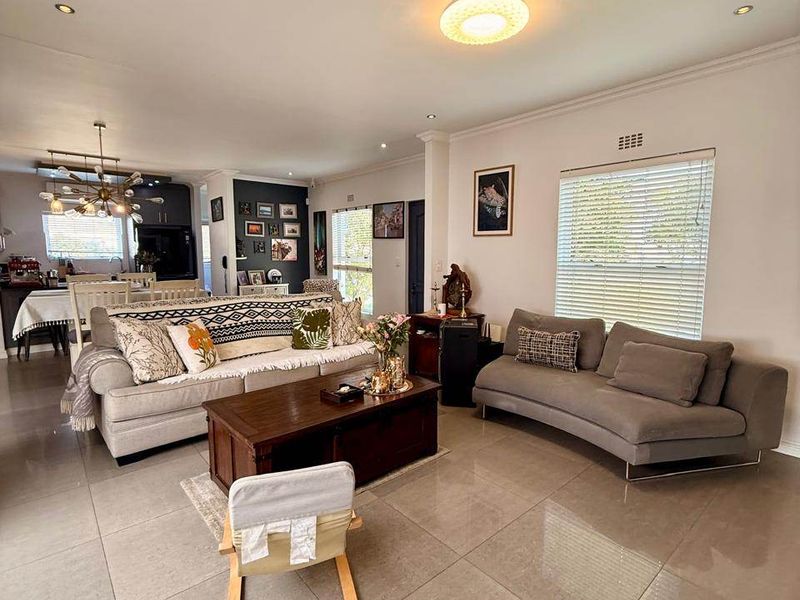 Spacious open-plan living area featuring large format porcelain floor tiles, recessed lighting, and a seamless transition to the adjacent kitchen space.