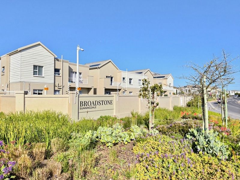 Exterior view of the Broadstone Sunningdale apartment complex, featuring modern building facades, perimeter security walls, and well-maintained landscaped gardens.
