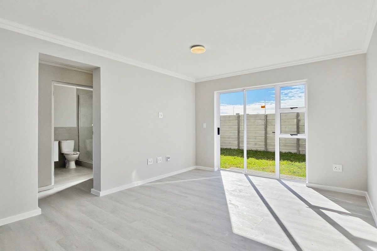 Bright and spacious living area featuring modern laminate flooring, coved ceilings, and a sliding glass door providing direct access to the rear garden.