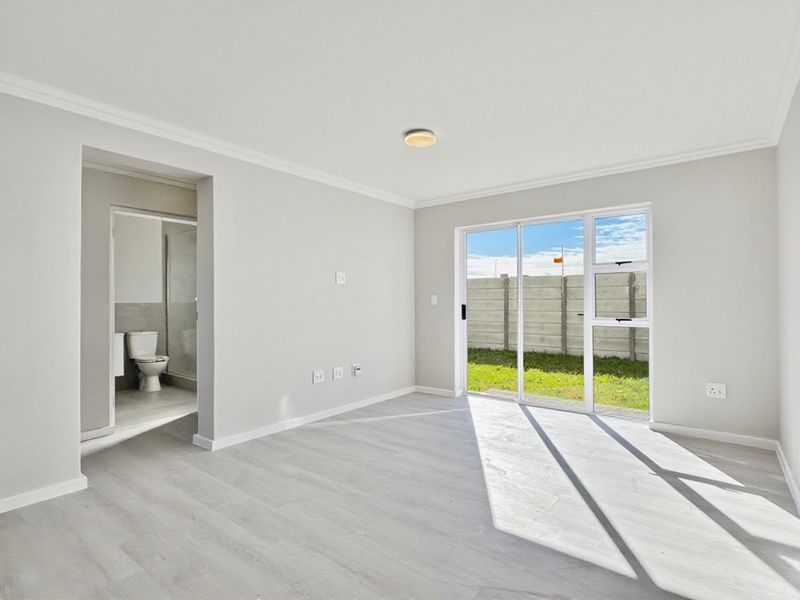 Bright and spacious living area featuring modern laminate flooring, coved ceilings, and a sliding glass door providing direct access to the rear garden.
