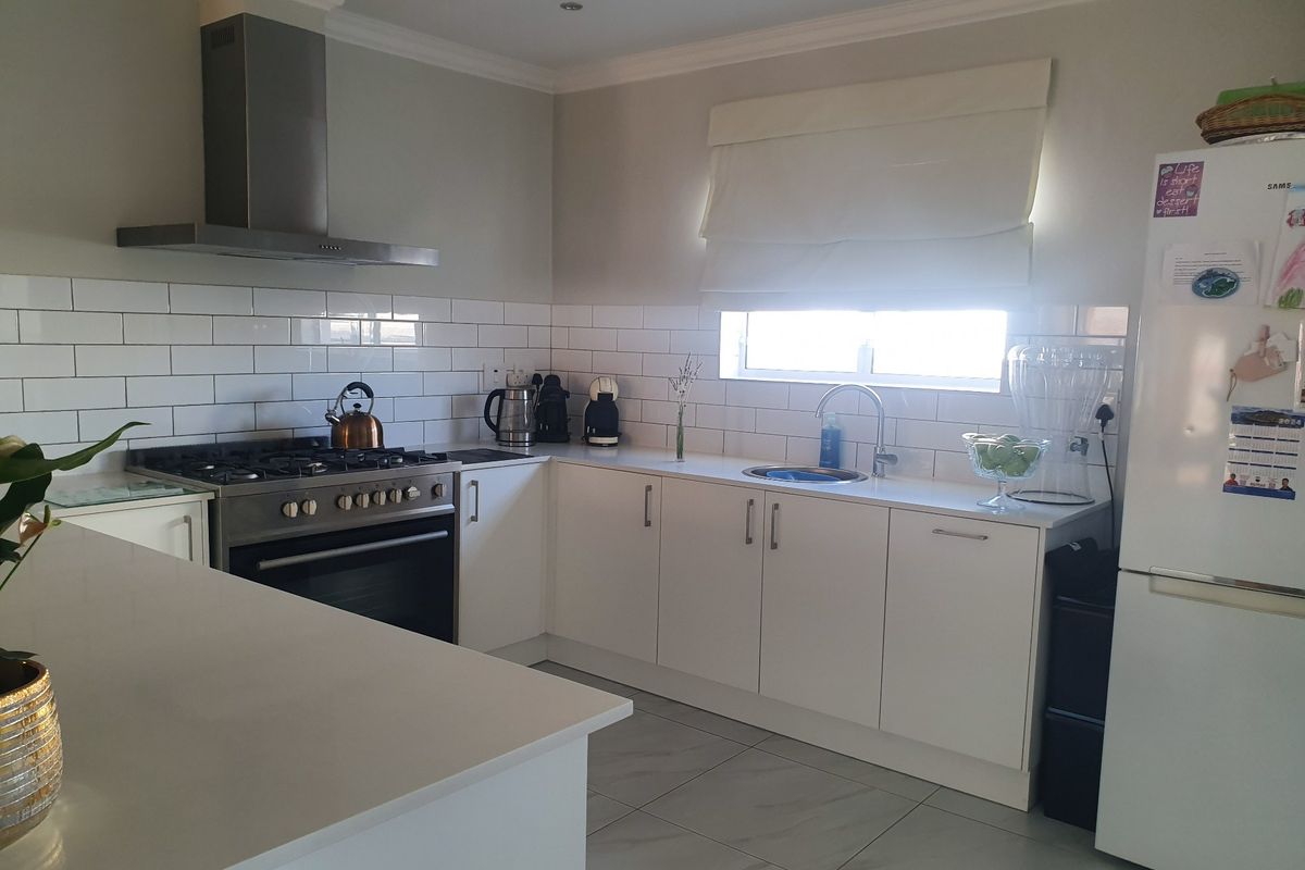 Modern kitchen featuring white cabinetry, subway tile backsplash, quartz countertops, and a stainless steel gas stove with an extractor fan.
