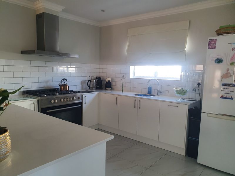 Modern kitchen featuring white cabinetry, subway tile backsplash, quartz countertops, and a stainless steel gas stove with an extractor fan.