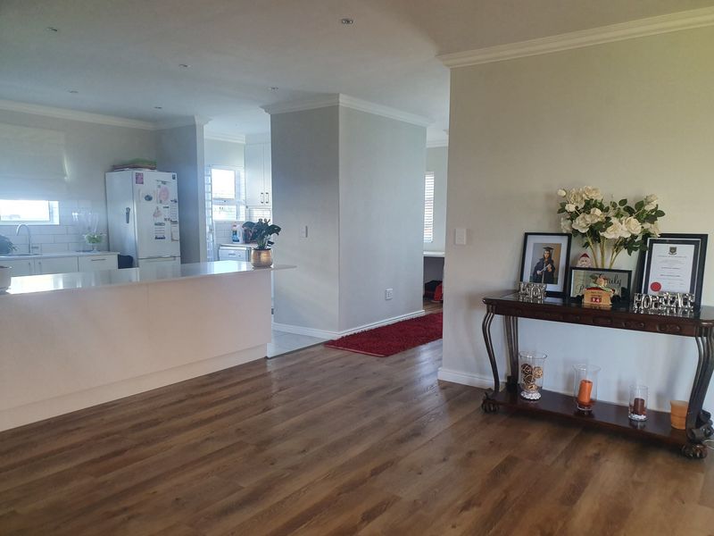 Open plan living area featuring modern laminate flooring, recessed lighting, and a functional kitchen island with a clean, neutral aesthetic.