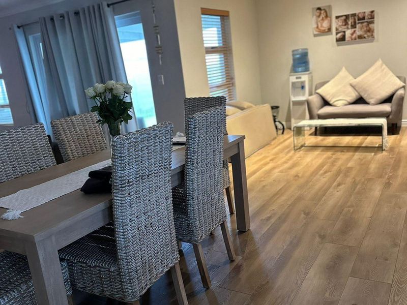 Spacious open-plan living and dining area featuring modern laminate flooring, recessed downlighting, and large sliding glass doors providing natural light.