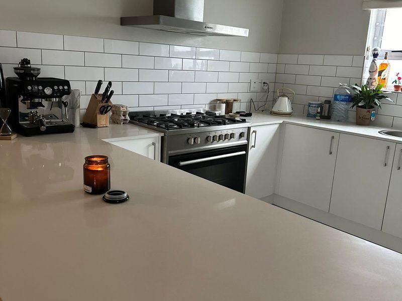 Modern kitchen featuring white cabinetry, quartz countertops, subway tile backsplash, and stainless steel appliances including a gas hob and extractor fan.