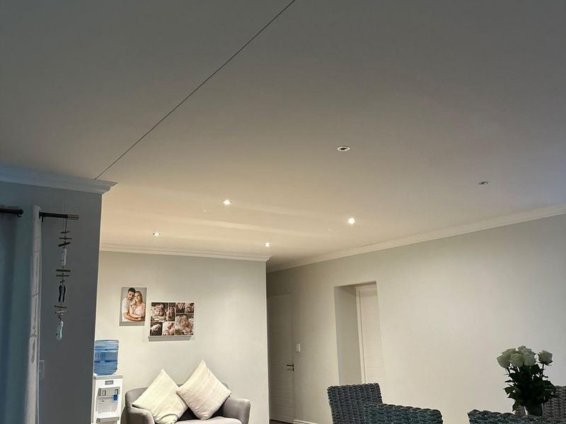 An open-plan living and dining area featuring modern laminate flooring, recessed downlighting, and neutral wall finishes.