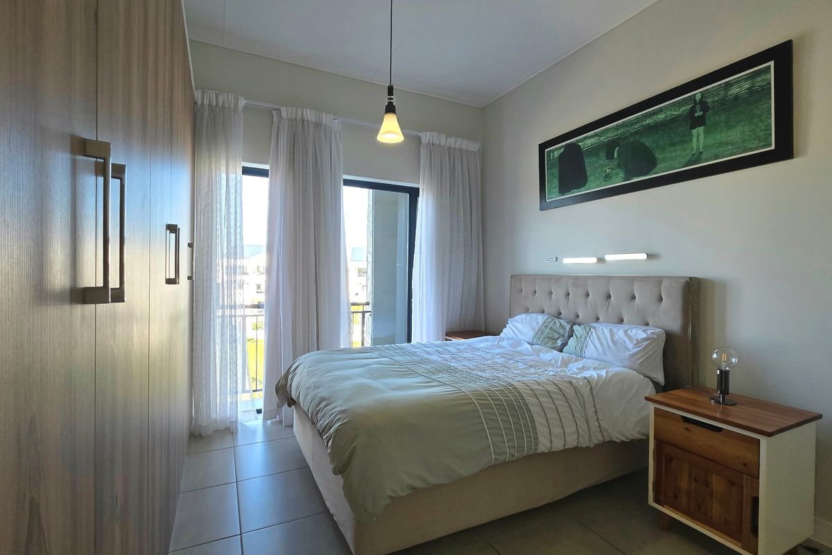 A well-maintained bedroom featuring built-in wardrobes, tiled flooring, and a sliding glass door providing access to a balcony.