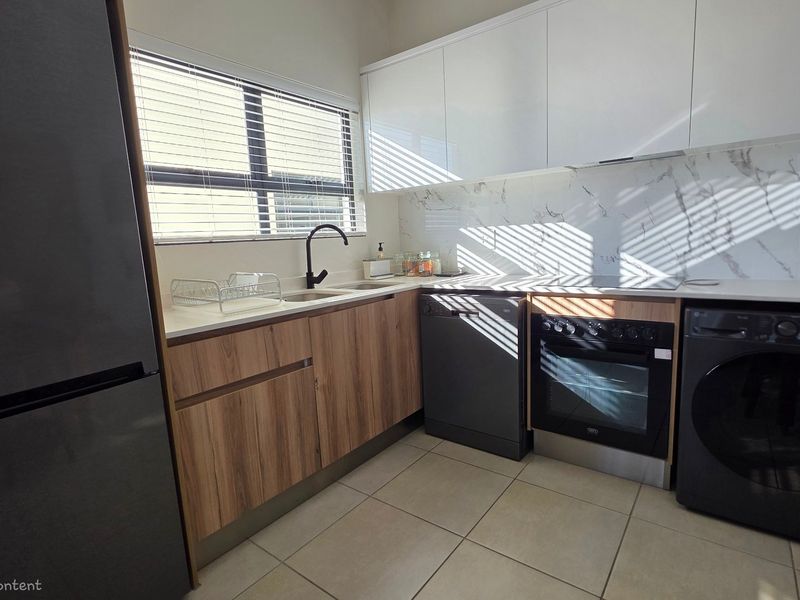 Modern kitchen featuring sleek white upper cabinetry, wood-grain lower cabinets, marble-look splashback, and integrated appliances including an oven and dishwasher.
