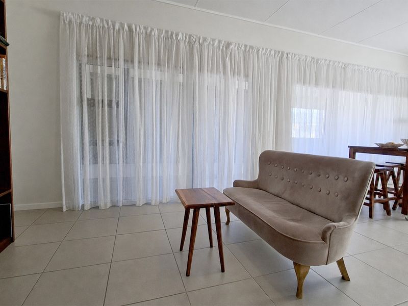 Open plan living area featuring large sliding glass doors, neutral tiled flooring, and a built-in shelving unit.