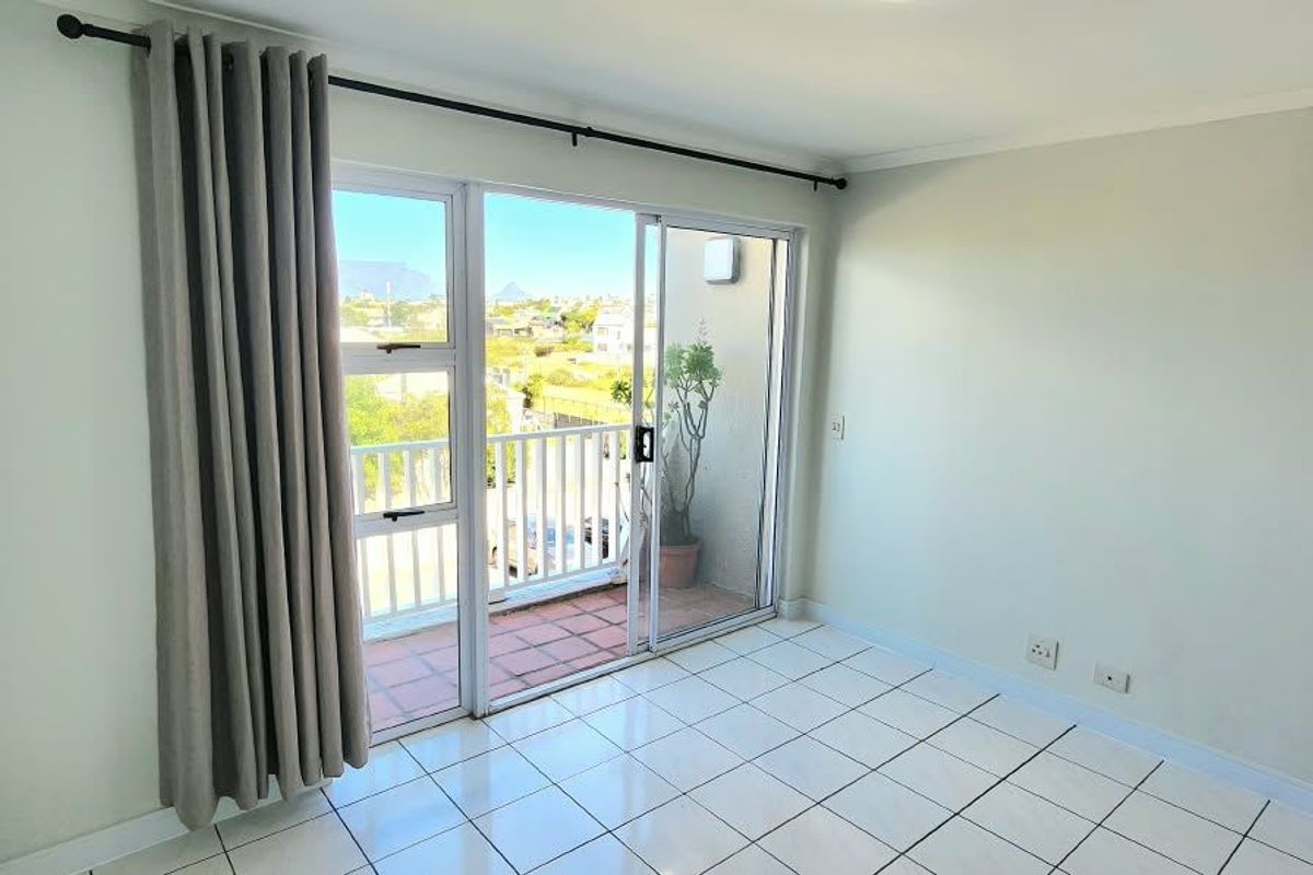 A bright, empty bedroom featuring tiled flooring and a sliding glass door that opens onto a private balcony.