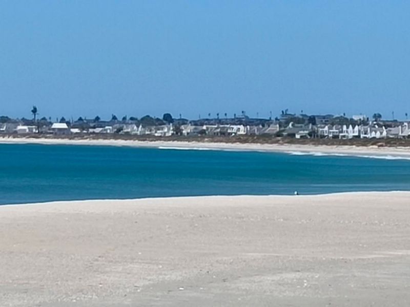 A scenic coastal view overlooking the sandy beach and the ocean with residential properties visible in the distance.