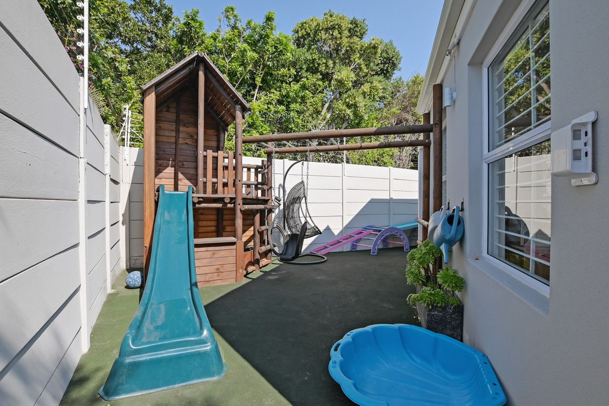 A private rear courtyard area featuring synthetic grass surfacing and high precast concrete boundary walls for privacy.