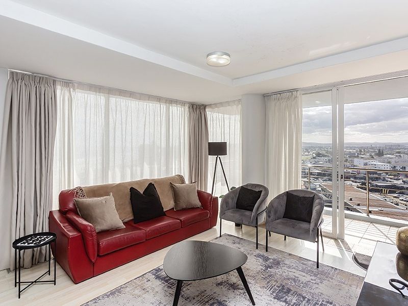 Bright living room featuring large floor-to-ceiling windows, tiled flooring, and direct access to a balcony with expansive city views.
