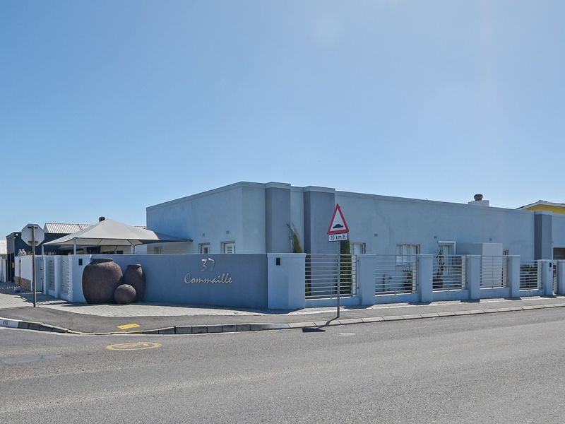 Street-facing view of the property featuring a modern boundary wall, metal fencing, and a paved entrance area.