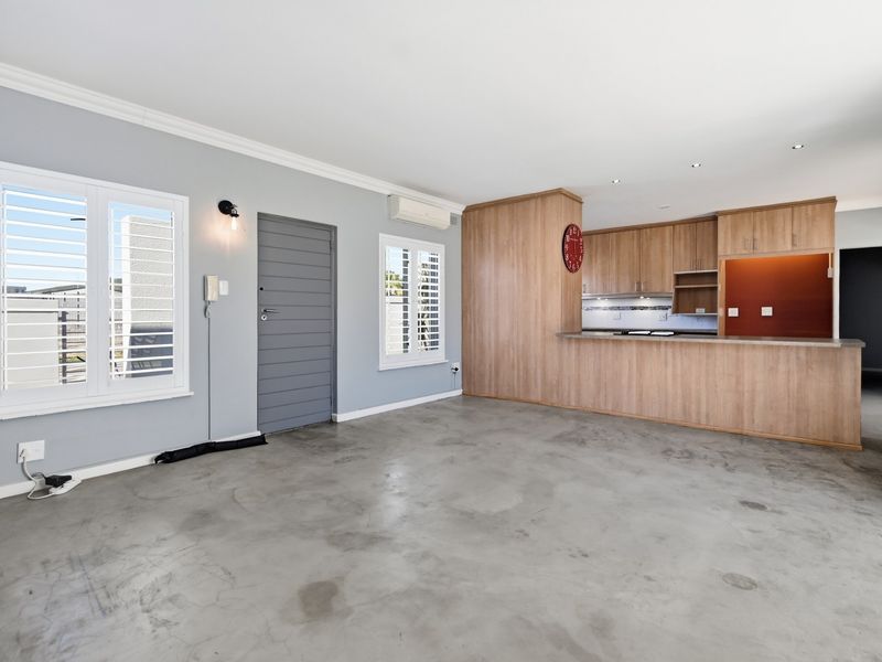 Open plan living area featuring polished concrete floors, a functional kitchen with breakfast bar, and plantation shutters, offering a versatile and modern layout.
