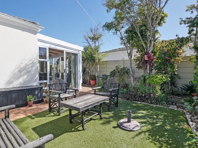 A private rear garden featuring a paved patio area, artificial lawn, and direct access to the home through sliding glass doors.