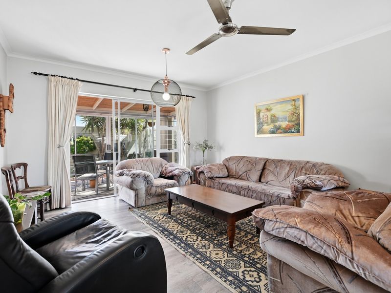 A comfortable living room featuring laminate flooring, a ceiling fan, and sliding glass doors that provide direct access to an outdoor patio area.