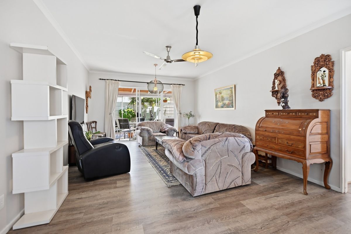 Spacious living room featuring modern laminate flooring, a ceiling fan, and large sliding glass doors providing direct access to the outdoor patio area.
