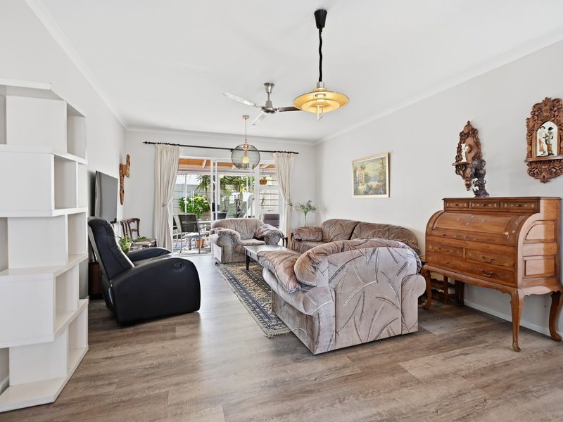 Spacious living room featuring modern laminate flooring, a ceiling fan, and large sliding glass doors providing direct access to the outdoor patio area.