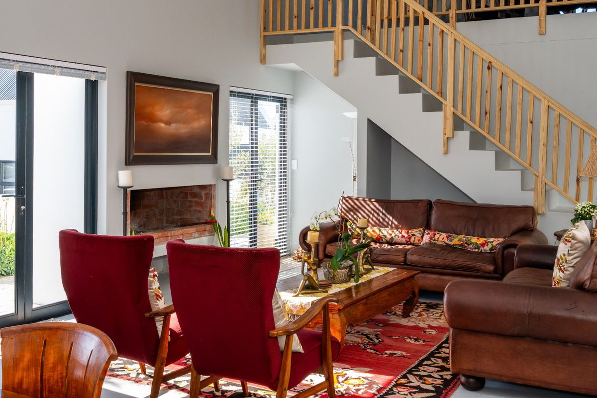 Spacious living room featuring a brick fireplace, staircase with wooden balustrade, and large sliding glass doors providing access to the outdoor area.