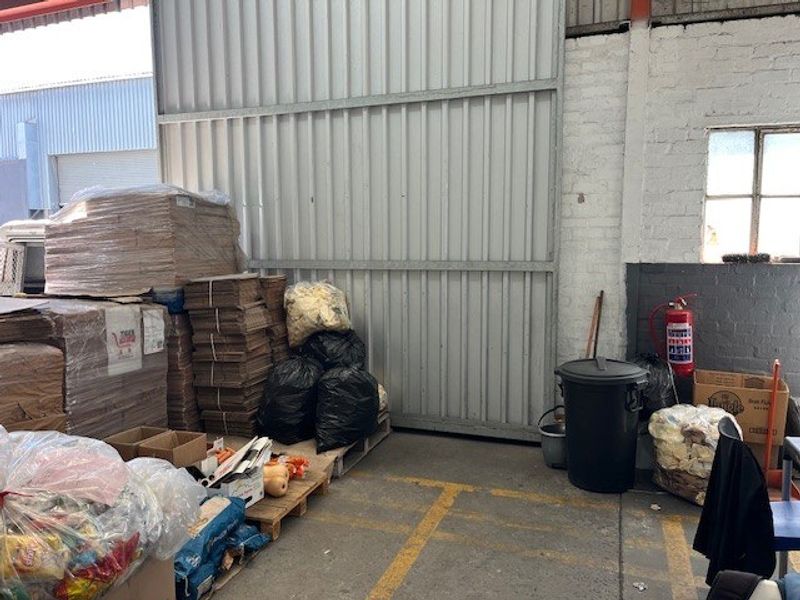 A commercial utility or storage area featuring a large sliding metal door, exposed brick walls, and concrete flooring with painted safety markings.