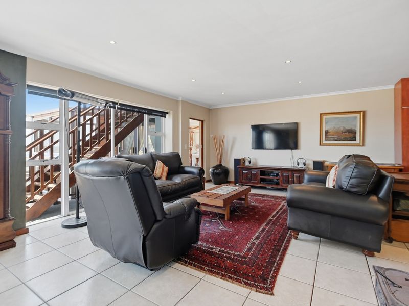 Spacious living room featuring tiled flooring, recessed downlights, and large sliding glass doors providing access to an external wooden staircase.