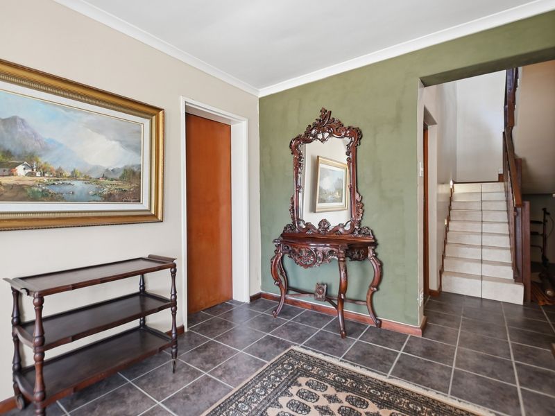 A welcoming entrance hall featuring tiled flooring and a staircase leading to the upper level, finished with a neutral and olive green accent wall.